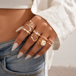 Close-up of gold layered rings set with pink hearts and pearls worn on a hand