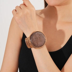 Close-up of vintage rose gold multilayer arm cuff featuring a large brown resin disk