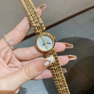 Elegant gold bracelet watch with a round dial by Dinimi, shown in a close-up handheld view