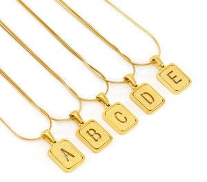 Gros plan de pendentifs lettres A-E en acier inoxydable plaqué or 18 carats avec sablage