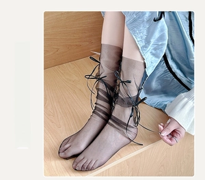 Detail of sheer black mesh socks with elegant ribbon bows for a sweet lolita style