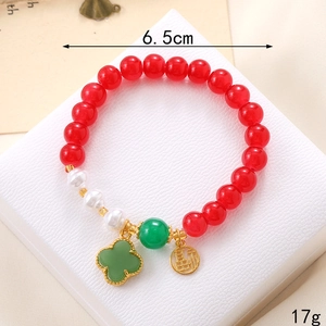 Vue macro d'un bracelet en agate rouge avec trèfle à quatre feuilles et détail de pièce Fu