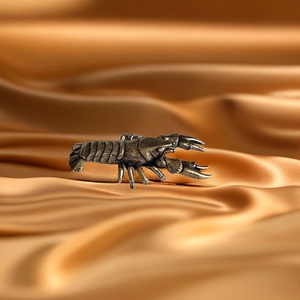 Detailed close-up of a vintage brass crawfish figurine on a golden silk background