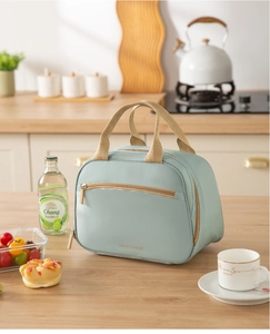 Close-up of mint green insulated lunch bag featuring dual zippers and woven handles