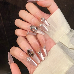 Purple cat eye press-on nails with long pointed tips, 3D crystals, and floral rhinestones