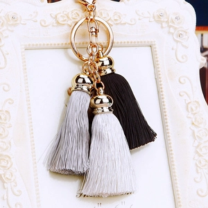 Close-up of gold clasp with elegant black, grey, and white silk tassels on a keyring