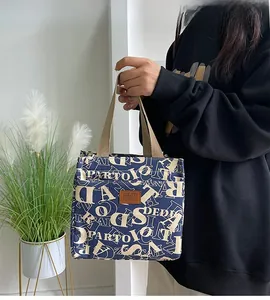 Détail du sac à déjeuner bleu marine avec imprimés de lettres et écusson en cuir