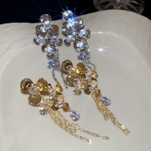 Macro shot of sparkling flower drop tassel earrings on a textured ceramic plate