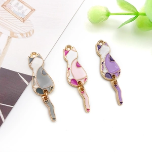 Detailed macro of three colorful enamel cat pendants with movable tails on white background