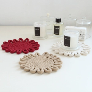 Trio of woven flower-shaped cotton coasters in red and beige for table heat protection