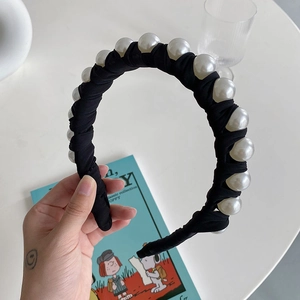 Close-up of black pleated fabric headband with large white pearls and classic texture