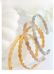 Three minimalist textured wave open bangles in gold, rose gold, and silver finishes