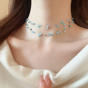 Macro shot of double layered necklace with blue opal cubes and silver beads on skin