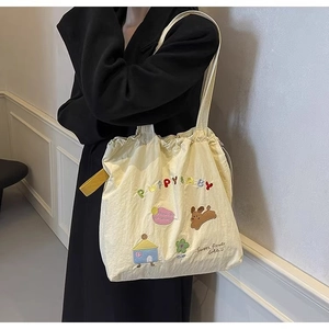 Detail of beige canvas tote bag with puppy and flower embroidery for daily school use