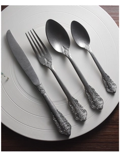 Macro shot of 304 stainless steel cutlery set with embossed vintage pattern on dark wood