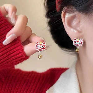 Detailed view of red and white Lion Dance earrings with small gold bells on model