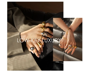 Artistic gold and silver fluid-style rings and bracelets worn against luxury suit fabric
