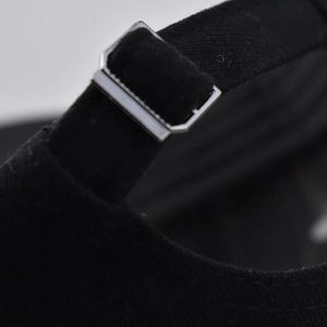 Close-up of the adjustable silver metal buckle and black fabric strap on a baseball cap