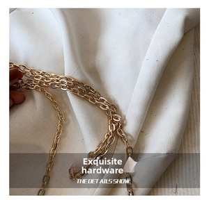 Detailed macro view of high-quality light gold metal chain strap on white fabric background