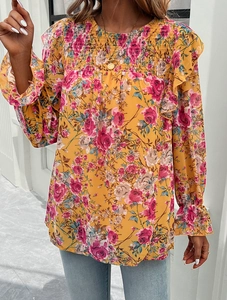 Detail view of yellow floral print blouse showing pleated round neck and ruffled cuffs