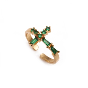 Detail of adjustable golden cross ring with inlaid green zircon on white background