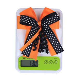 Detail shot of a double-layered Halloween bow hair clip on a scale weighing 13 grams