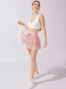 Detail of pink high-waisted pleated sports skort with drawstring and mesh fabric layers