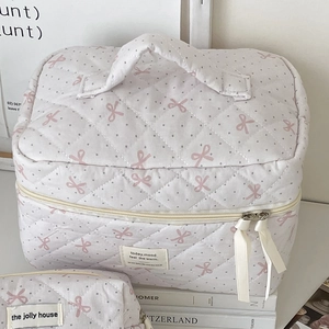 Quilted makeup bags with pink bow print and ribbon zipper detail in lifestyle setting