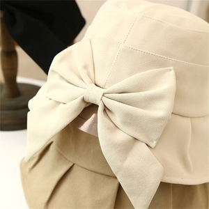 Close-up of beige cotton sun hat featuring a delicate bow and high-quality fabric texture