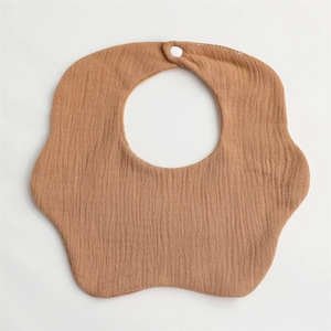 Detail view of brown cotton gauze baby bib with petal edge and white snap button closure