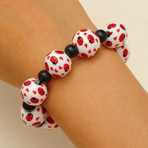 Gros plan du bracelet perlé avec motifs coccinelle et cœur sur perles blanches et noires
