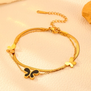 Detail of gold layered butterfly bracelet with black shell pendant and flat snake chain
