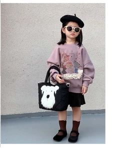 Detail of a black quilted shoulder bag featuring a cute white dog face for children