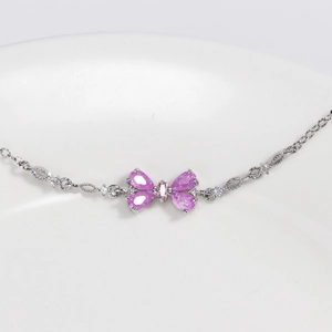 Detailed close-up of a silver bracelet featuring a pink butterfly-shaped zircon pendant
