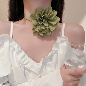 Close-up of a large green fabric flower choker with ribbon on a woman's neck