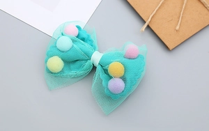 Detail of blue tulle bow hair clip for girls featuring colorful soft pom-pom accents