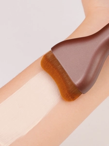 Macro shot of wide flat foundation brush applying cream foundation smoothly on skin