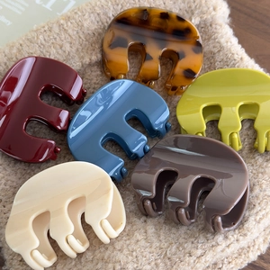 Detailed collection of colorful acrylic M-shaped hair claws on soft beige plush background