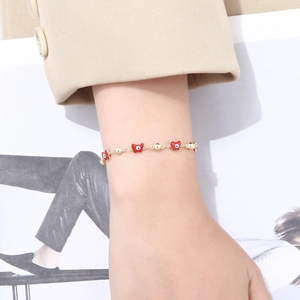 Nahaufnahme eines Armbands mit rotem Schmetterling und goldenen Perlen am Handgelenk