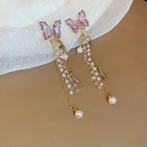 Macro detail of purple crystal butterfly and long gold tassel fringe with pearls