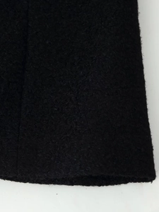 Close-up of black woolen fabric showing thick grainy texture and warm material details