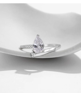 Macro shot of silver teardrop diamond ring on wave prop showing high sparkle and detail