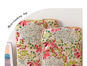 Detail of floral embroidery on off-white fabric laptop sleeve with golden zipper