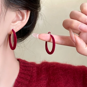 Close-up of red flocked hoop earrings on model highlighting plush velvet texture