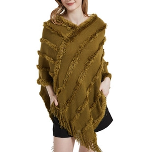 Detail of knit poncho with long diagonal tassels and soft mustard yellow fabric