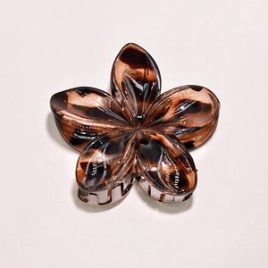 Macro view of retro tortoise shell floral hair claw with glossy resin texture and teeth