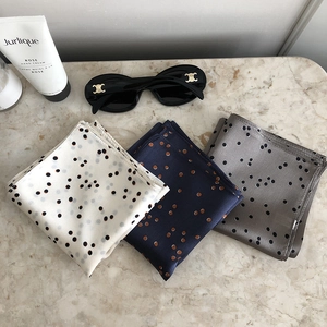 Detail view of premium silk scarfs in polka dot patterns on a textured marble background