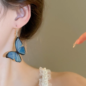 Close-up of elegant gradient blue butterfly earring with translucent resin texture