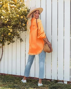 Detail view of orange denim jacket with frayed hem and distressed back design