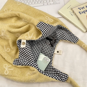 Détail intérieur du sac peluche jaune avec doublure à carreaux, téléphone et lunettes